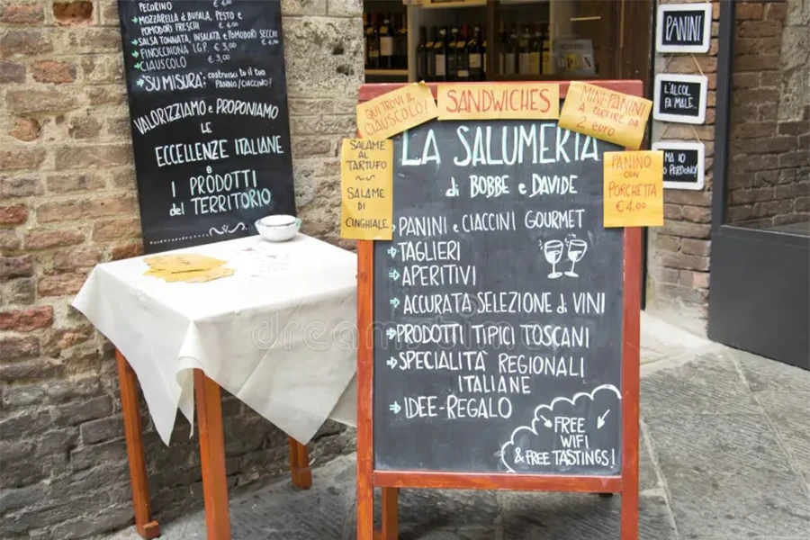 Foto de um menu do dia (menu fisso) escrito em um quadro negro na frente de uma trattoria